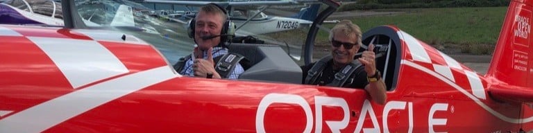 OnPlan partner Jim Williamson joined acrobatic aviator champion Sean D. Tucker for an excursion in the official Oracle plane. Both smiling and giving a thumbs up.